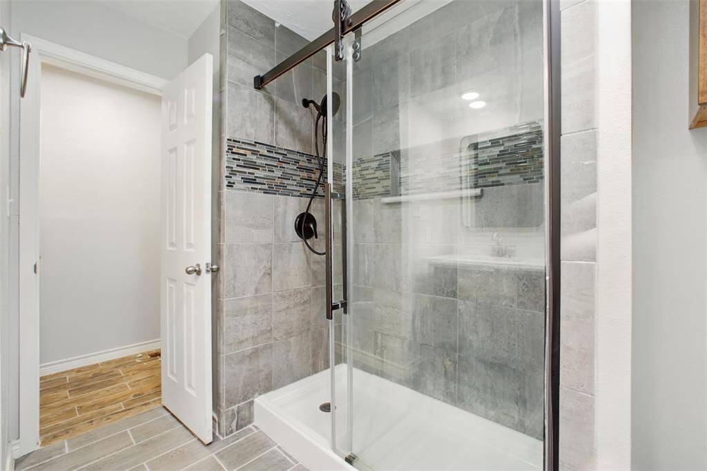 The ensuite bath is beautifully updated with a glass-enclosed shower boasting floor to ceiling custom tile backspash for a touch of spa-like luxury.