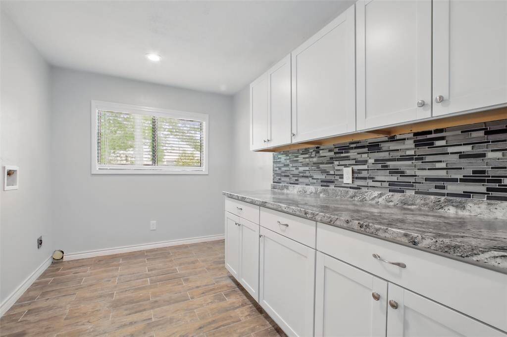 Thoughtfully designed for function and flow, the utility room features granite countertops and shaker-style upper and lower cabinets—offering ample storage and a convenient surface for folding, sorting, or organizing daily essentials.