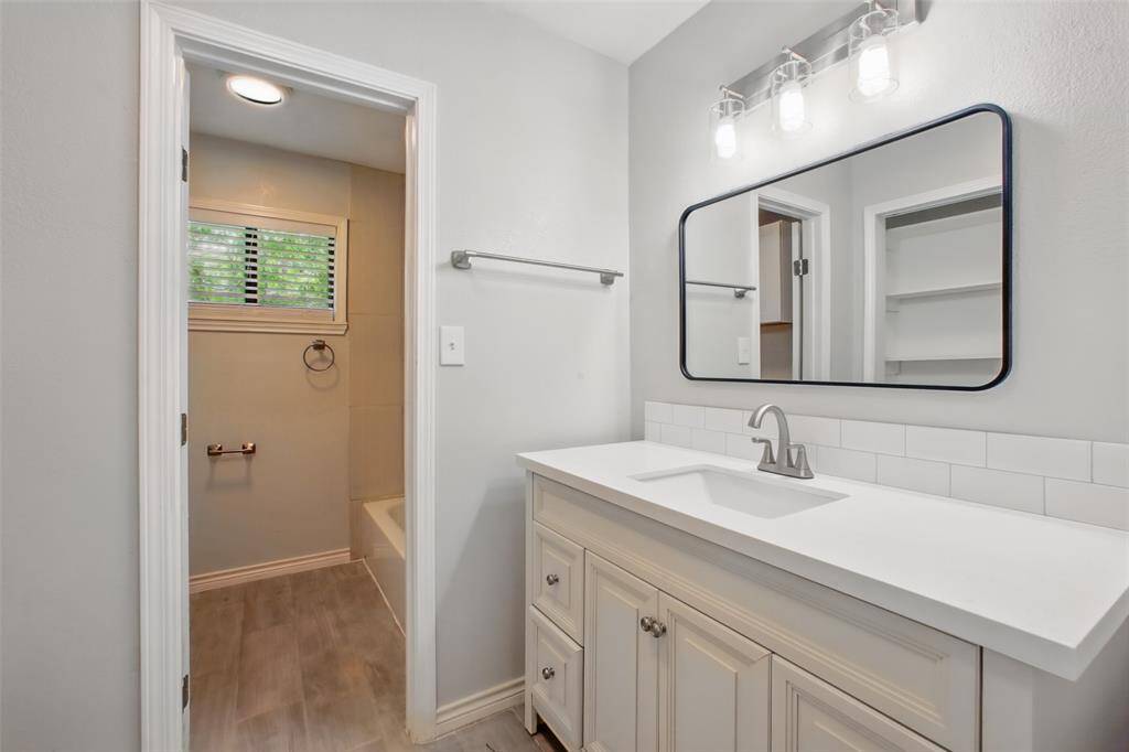 Clean and modern, this bathroom offers updated finishes including sleek tile backsplash and thoughtfully selected designer fixtures.