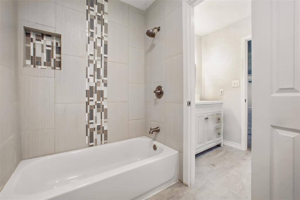 Updated with custom tile backsplash and cohesive lighting—every detail of this shower/tub combo feels elevated.