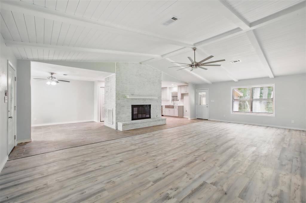 Natural light fills this spacious living area, where vaulted ceilings and a white brick surround create texture, height, and comfort.