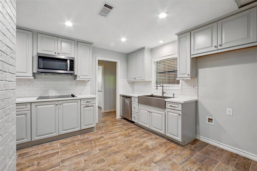 Grey shaker-style cabinets and white subway tile lend a fresh, contemporary feel that perfectly complements the kitchen’s warm, welcoming tone.