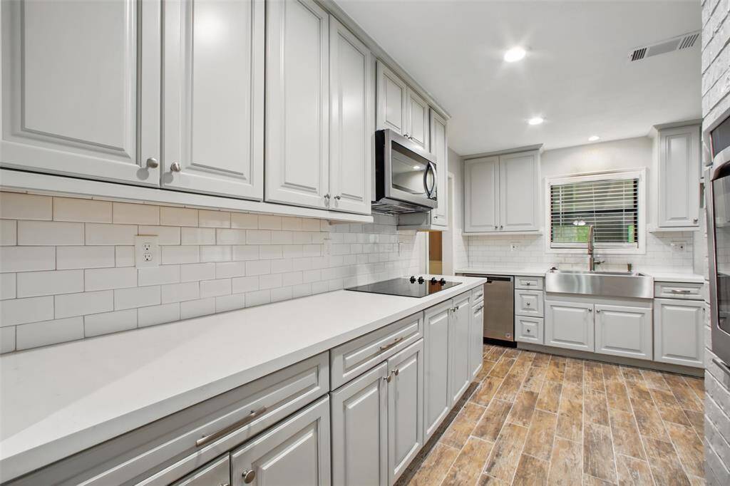 This galley-style kitchen blends classic finishes with modern function—featuring quartz countertops, grey transitional cabinetry, and a white subway tile backsplash that adds timeless character.