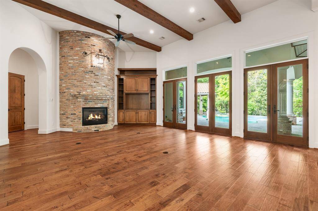 The open-concept family room features a stunning brick fireplace and a wall of transom windows and doors that flood the space with natural light and offer seamless indoor-outdoor living.