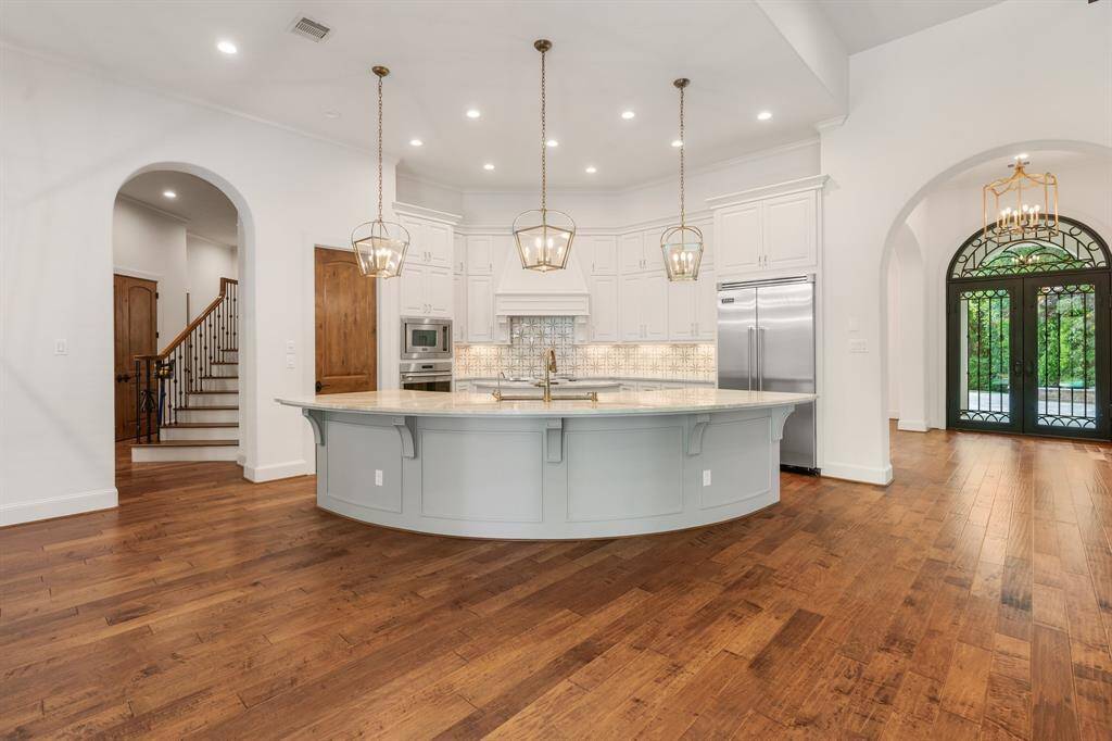 A trio of pendants illuminate the kitchen island with generous seating, Taj Majal Quartzite counters and storage.