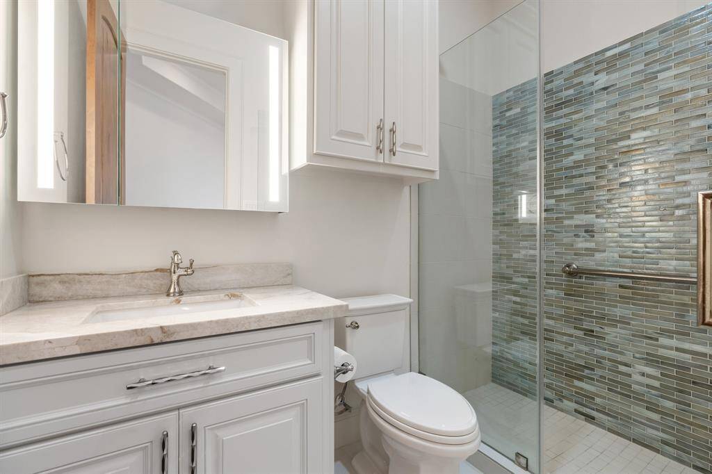 Bedroom #2 En Suite Bath: boasting all new walk-in shower with rail, tile flooring and shower wall, quartzite counter, hardware, toilet and Kohler medicine cabinet.