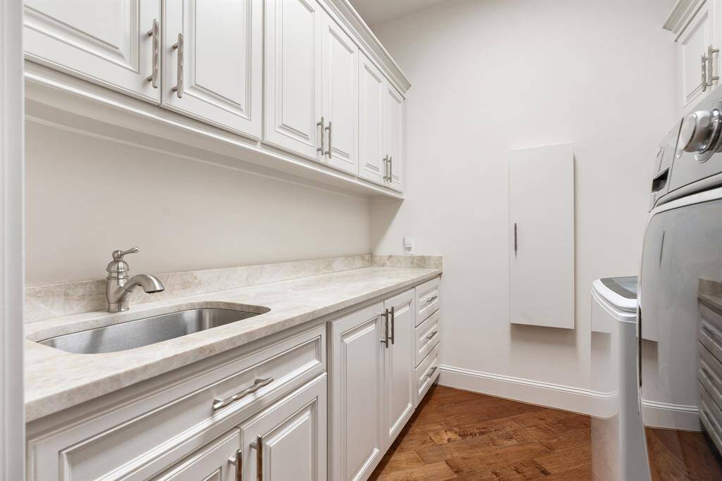 The remodeled laundry room includes ample storage, a sink, built-in ironing board, and comes complete with washer/dryer.