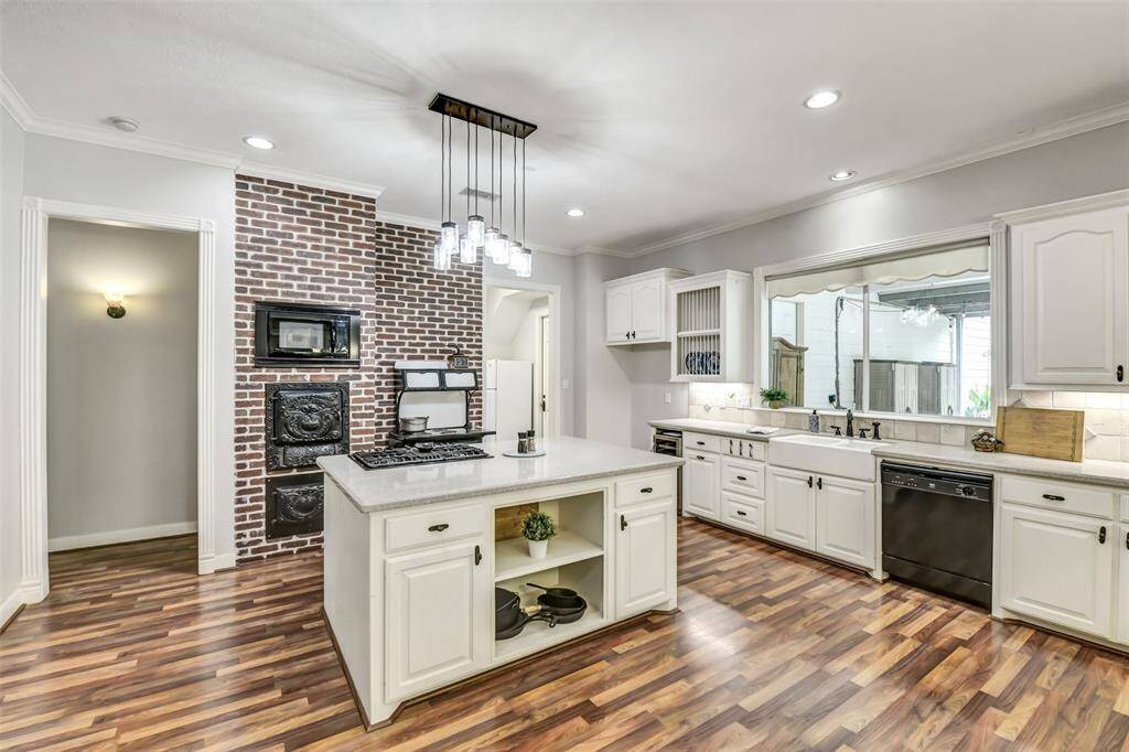 Farmhouse sink with large window overlooking back patio.  Island with storage, decorative plate storage, wine fridge, and OMG look at the Cast iron Antique styled built-in oven and Cast Iron Stove!!!