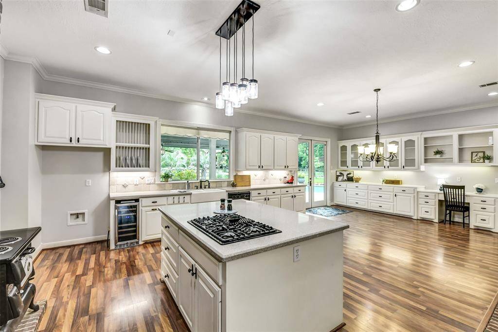 This kitchen is perfect for holiday parties, displaying your favorite collections. French doors off of the kitchen lead to the pool and outdoor living space. Love the gas cooktop and wine fridge!