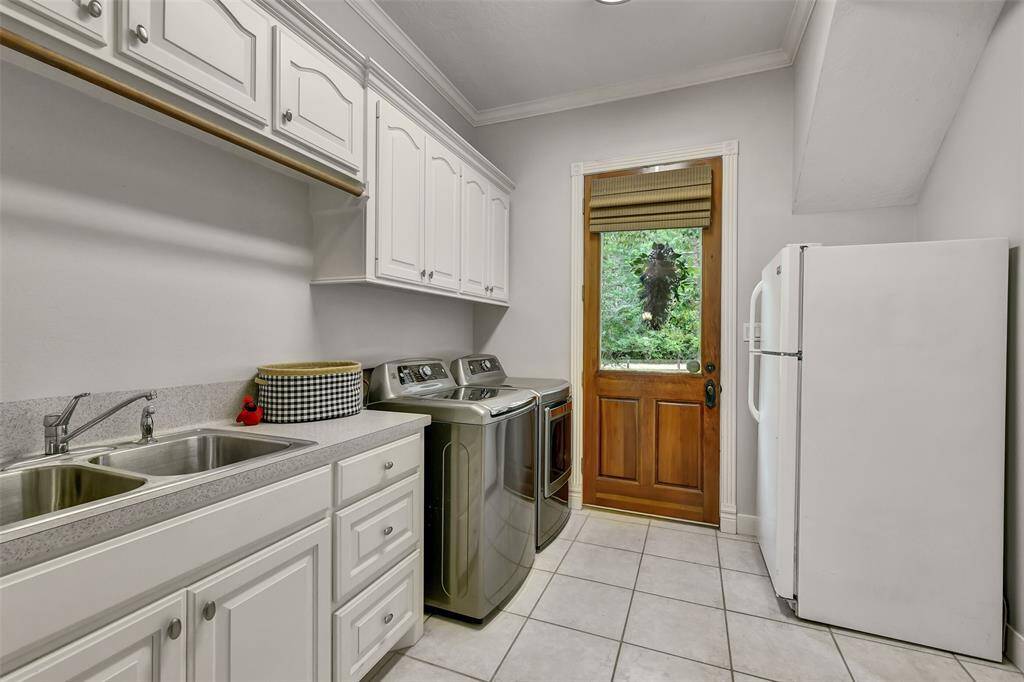 Laundry room is right off of the kitchen and also features a HUGE walk-in pantry. Has door to side of home, with a covered porch. Laundry room has a double sink, workspace, storage, and room for a fridge or freezer.