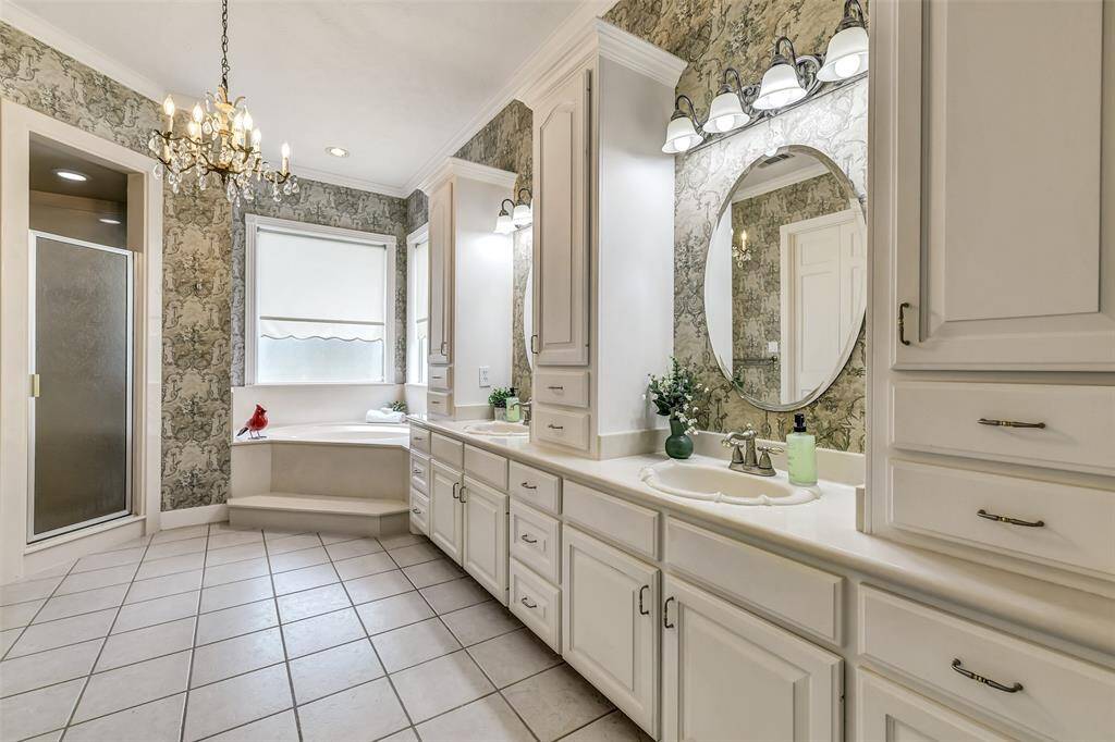 Vintage styled bath with a large corner soaking tub, walk in shower, dual sinks and an abundance of storage! Vintage Crystal light fixture can stay!