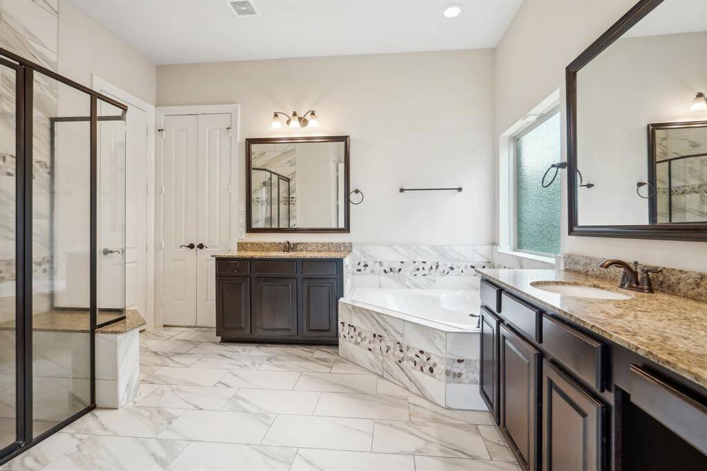 Beautiful tiled bath with separate vanities, jetted tub and bench shower.