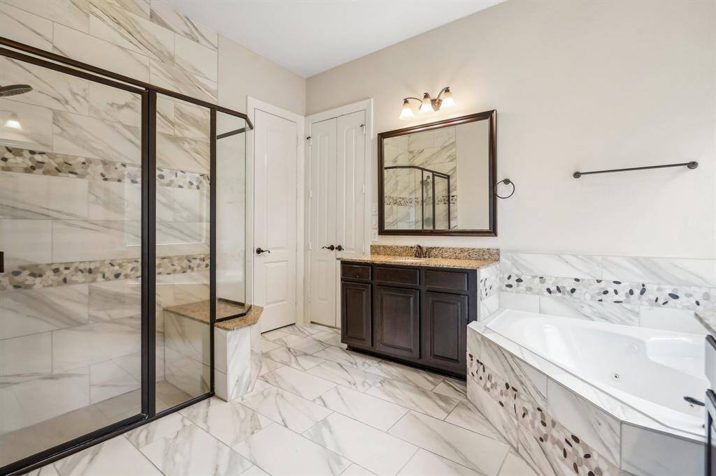 Custom tile inserts, jetted tub, and a large shower with bench make you feel pampered.