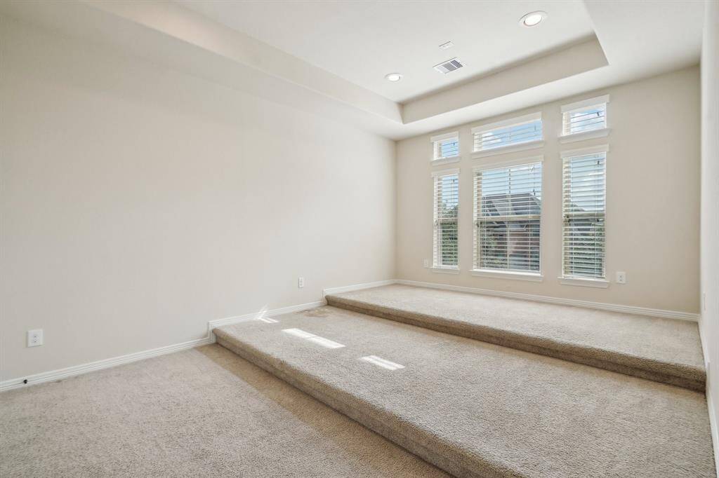 Media room features tiered seating and tray ceiling. Room for the projector and retractable screen.
