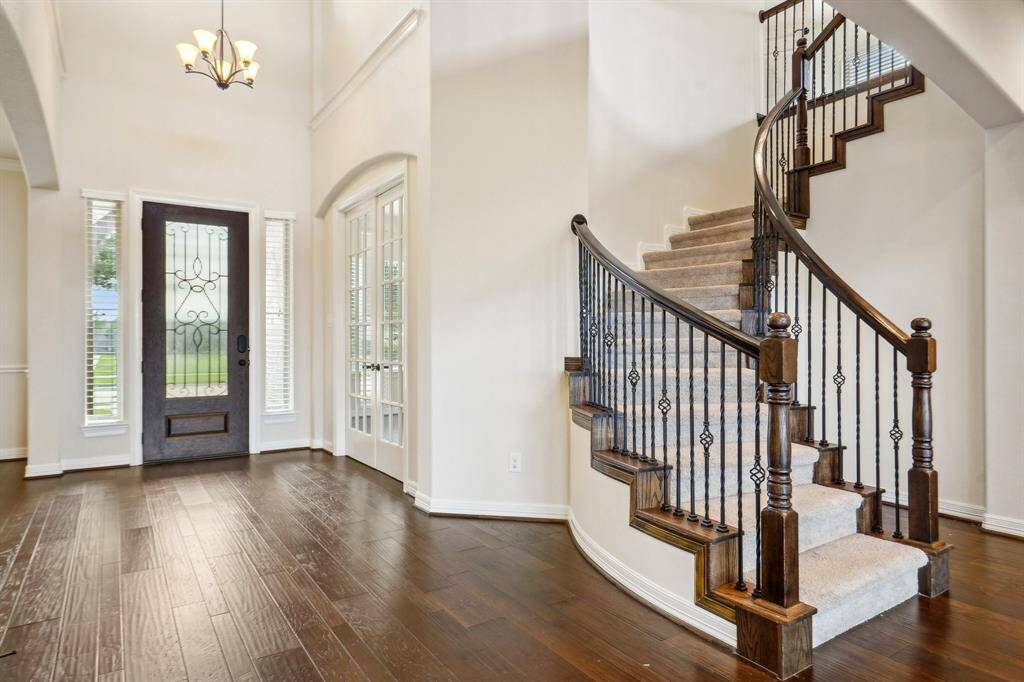 Grand foyer showcases beautiful 3/4 glass/wrought iron door, soaring ceilings, and fabulous curved stairwell with designer spindles.