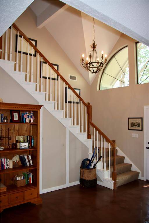 A dramatic entryway welcomes you with soaring ceilings, an iron chandelier, and views of the stairway bathed in natural light.