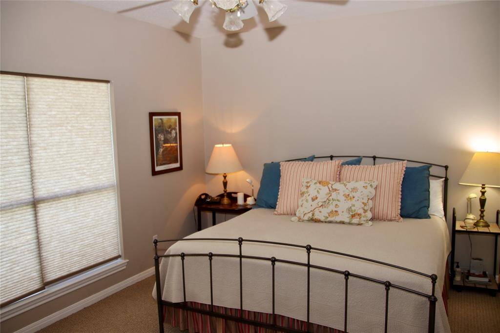 This cozy primary suite offers a quiet corner to unwind, featuring soft lighting, neutral tones, and charming cottage details.