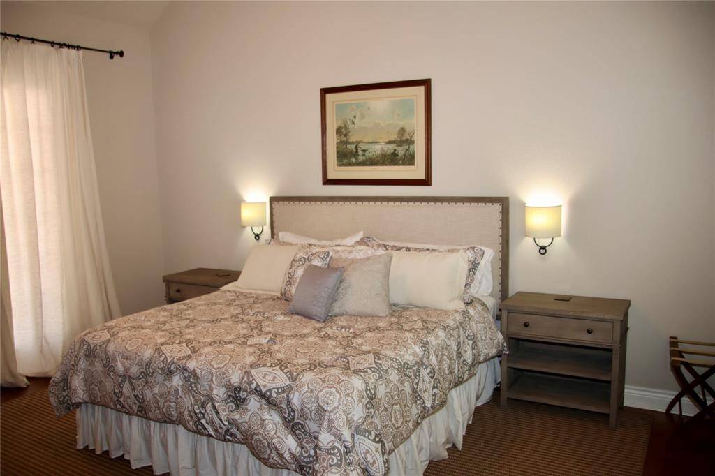 The primary suite located in the guest house exudes comfort with its calming palette, plush bedding, and warm lighting—your private retreat after a day on the water.