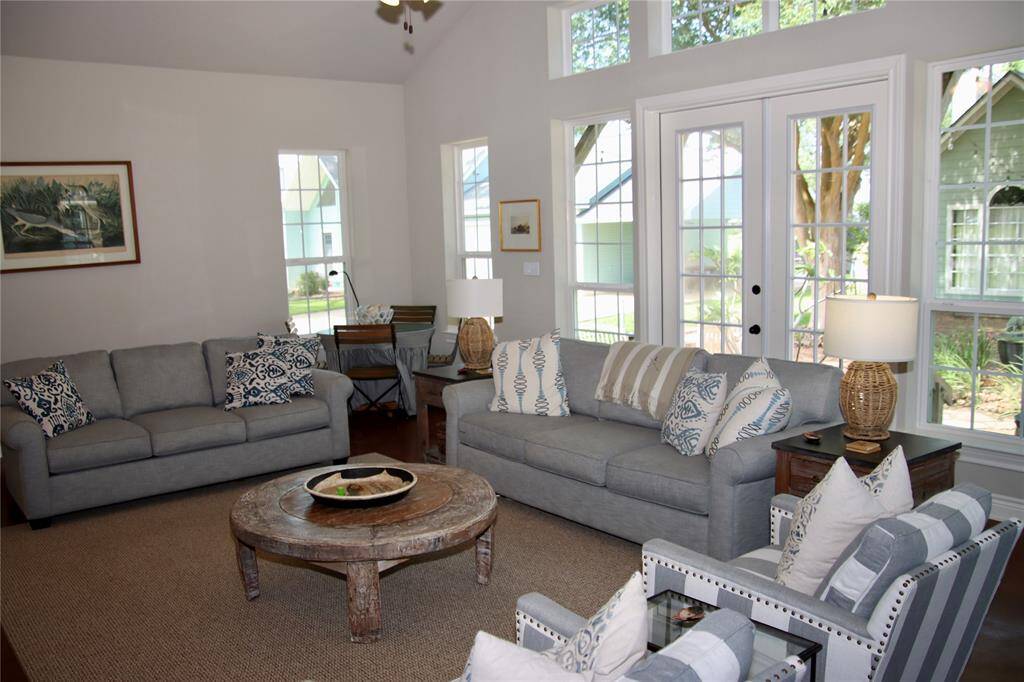 Soaked in natural light, the living room welcomes conversation and relaxation with tall windows, layered textures, and effortless coastal style.
