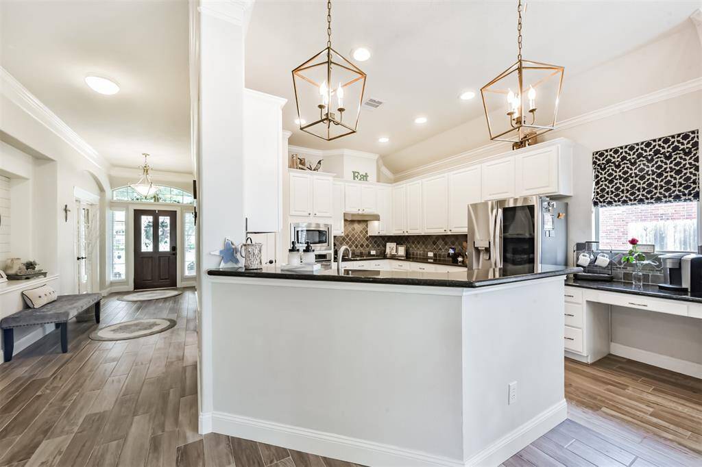 A view showcasing the foyer, service bar, recessed art niche, and kitchen.
