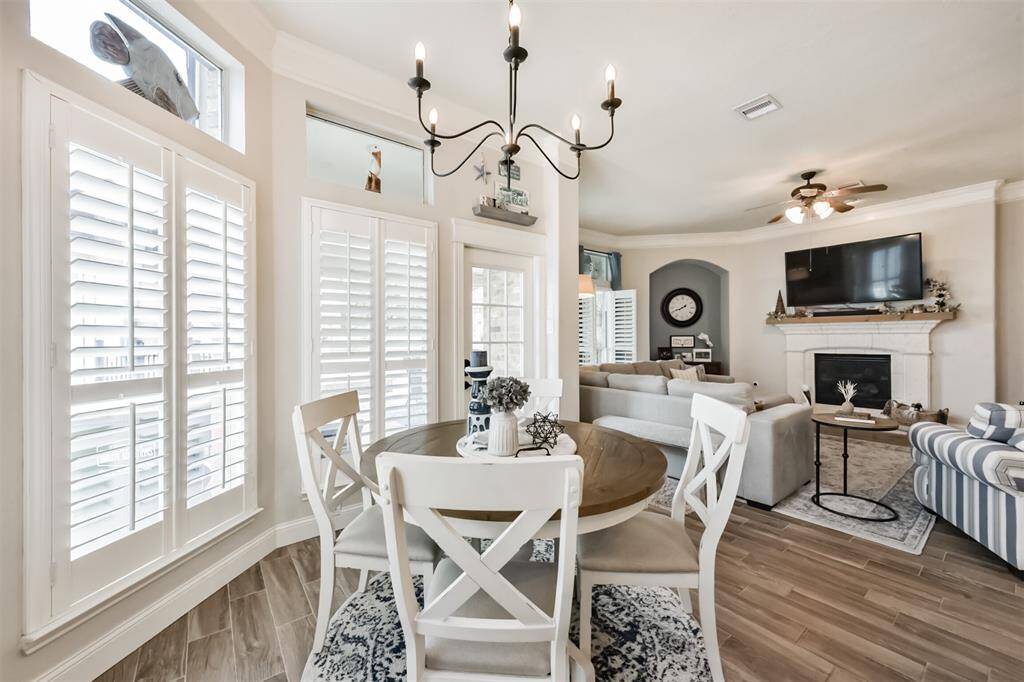 A charming breakfast room featuring bay windows and elegant plantation shutters seamlessly connects to the living room. A door leads directly to the pool and spa area, creating a perfect blend of indoor and outdoor living.