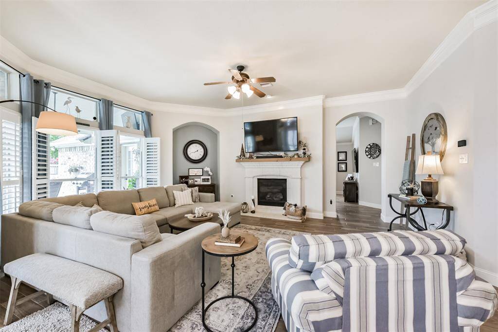 A spacious family room featuring a stunning wall of windows, an elegant arched niche, and a charming stone-accented fireplace.