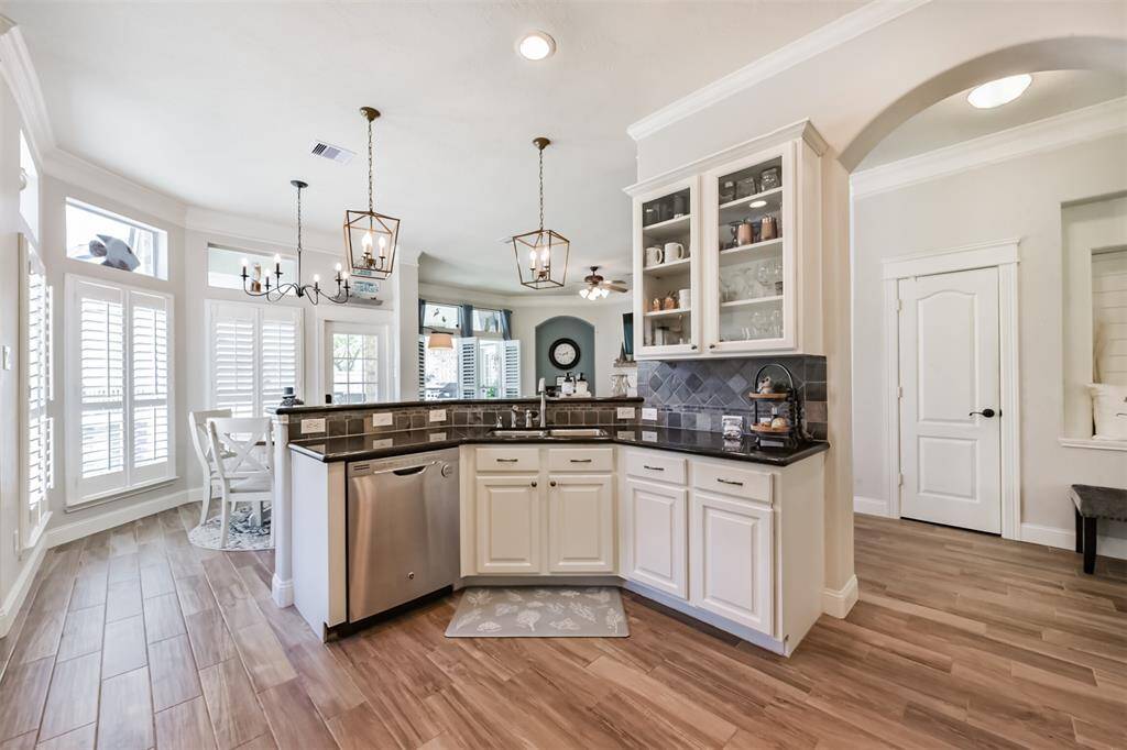 A stunning view of island-style counters, a bay window, and plantation shutters, all overlooking the pool and spa.