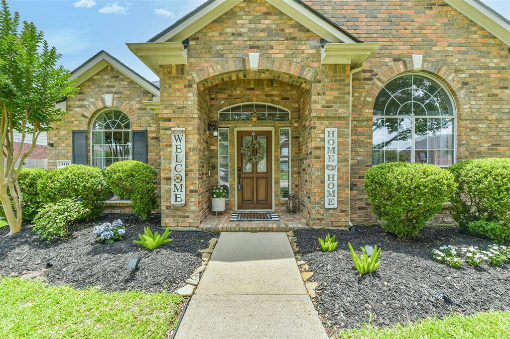 Beautiful all-brick home featuring a charming covered front porch with brick pavers and a solid wood front door adorned with beveled glass. Elegant keystone accents complete the timeless design..