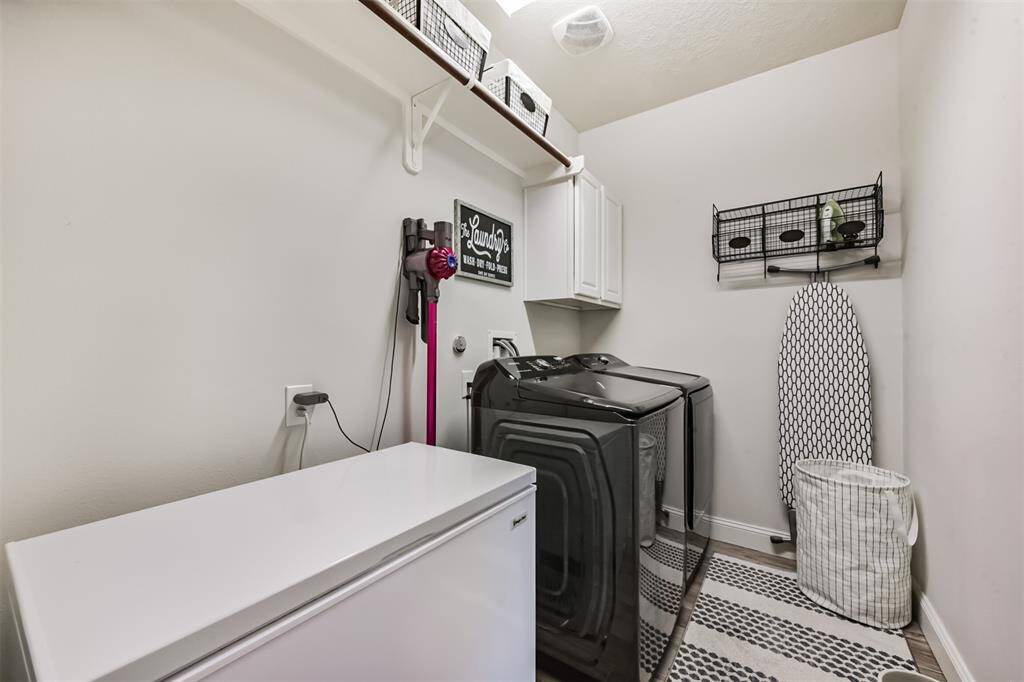 A utility room featuring a freezer, cabinetry, and a storage shelf with wooden dowels for added functionality.