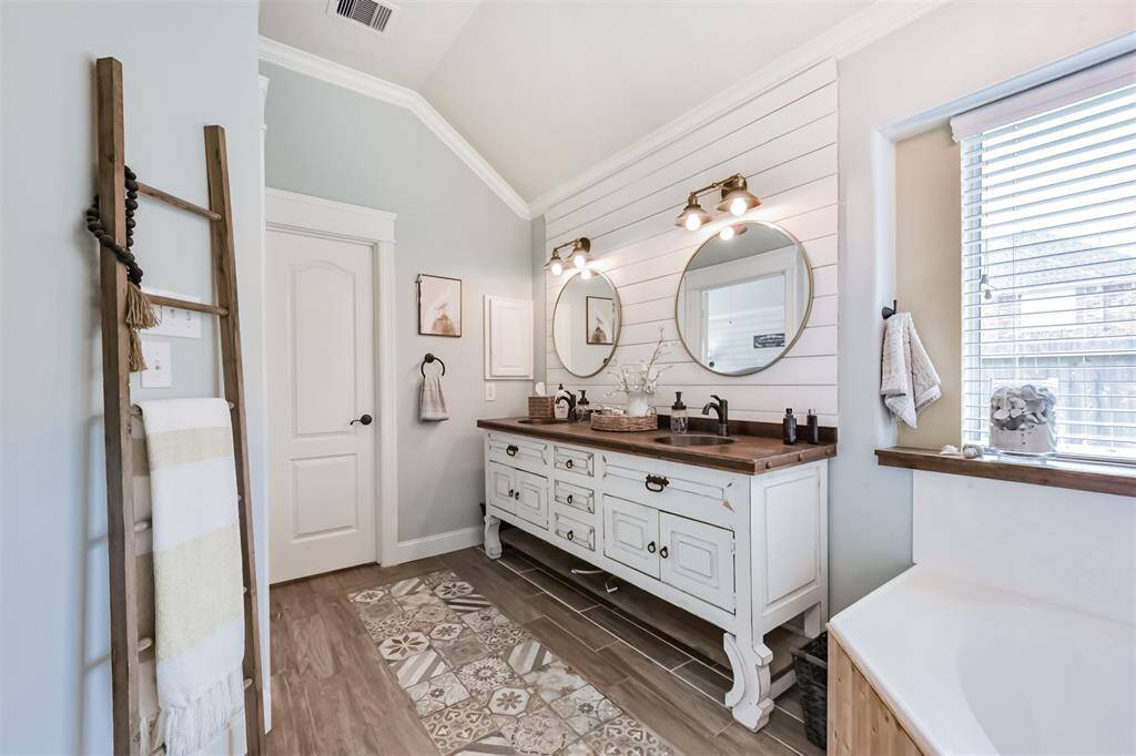 The en-suite boasts a sleek designer vanity cabinet complemented by a stylish shiplap accent wall.