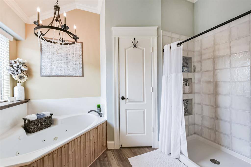 Spacious primary bedroom featuring a luxurious jetted tub and a separate walk-in shower elegantly enclosed with ceramic tile.