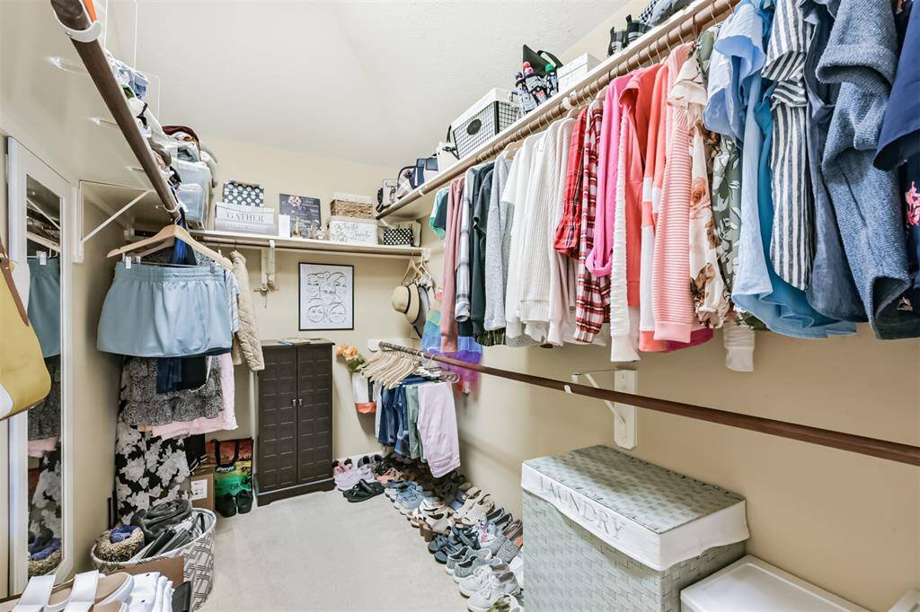 A walk-in closet featuring spacious storage shelves and elegant wooden dowels.