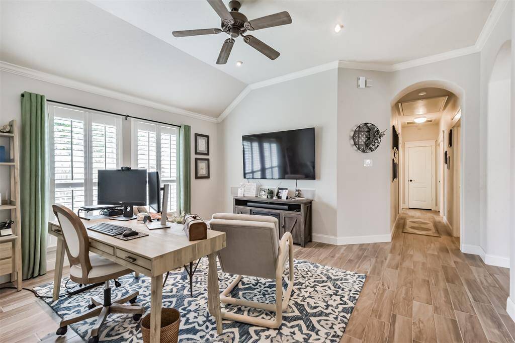 Elegant media room featuring crown molding, arched entryways, and sophisticated plantation shutters.
