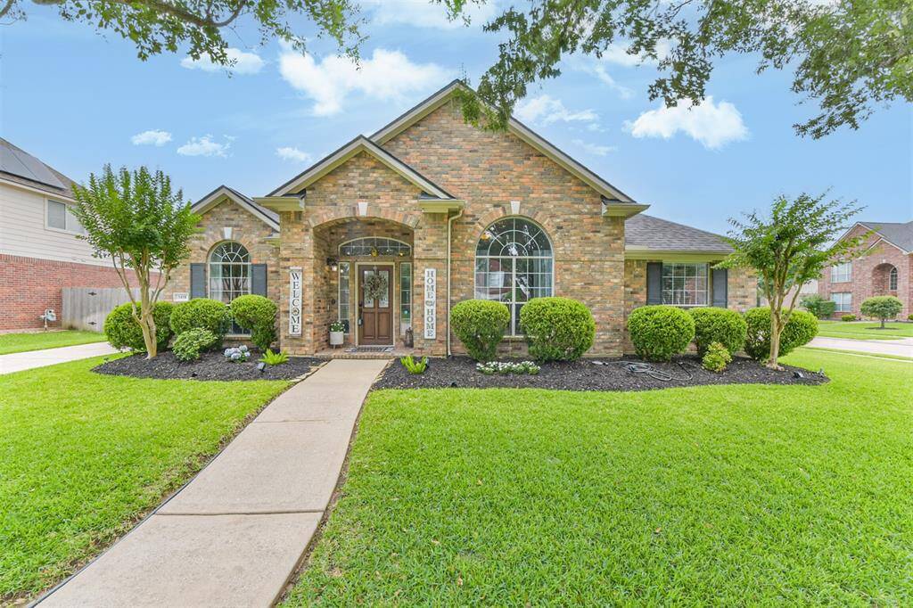 Elegant arched windows, decorative keystones, and vibrant lush landscaping.