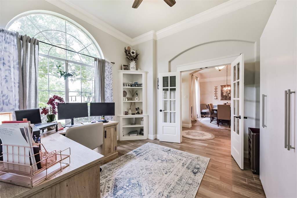 French doors open into the office or study, featuring a built-in corner bookshelf for added functionality and charm.