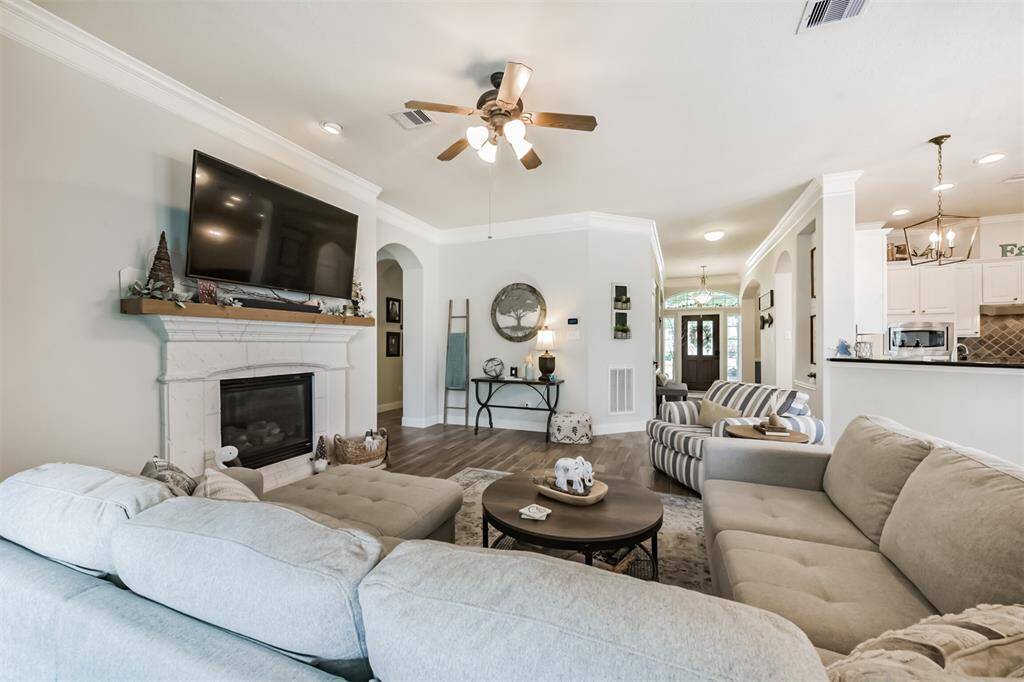 Gas log fireplace with stone accents, elegantly rounded sheetrock, and an arched entryway leading to the hallway. Soaring high ceilings complete the space.