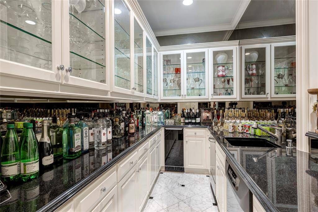 The wet bar seamlessly opens to the Grand Hall, featuring top-of-the-line amenities including an ice maker, beverage refrigerator and dishwasher. With generous storage for glassware, the upper cabinets boast stunning glass fronts, making this space not only functional but also visually striking. It's the perfect setting for entertaining and creating memorable experiences.
