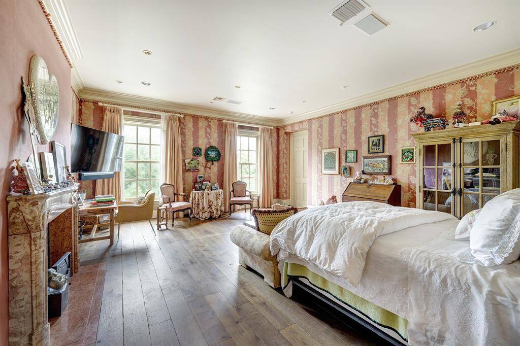 Custom fabric wall covering enhanced by designer drapes. The spacious primary suite features a wood-burning fireplace, built-in speakers, and beautiful crown molding.