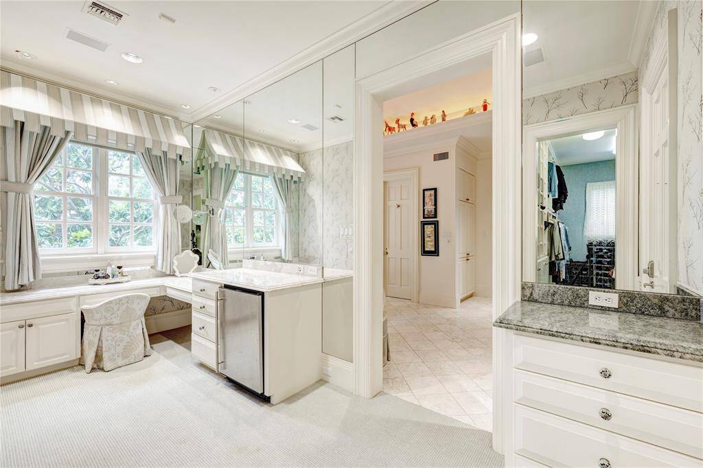 The primary suite offers dressing area with a variety of amenities, including a vanity, beverage counter, and built-in dressers. The dressing area is complete with a cedar closet, plus two walk-in closets equipped with shoe racks and built-in dressers for ample storage space.