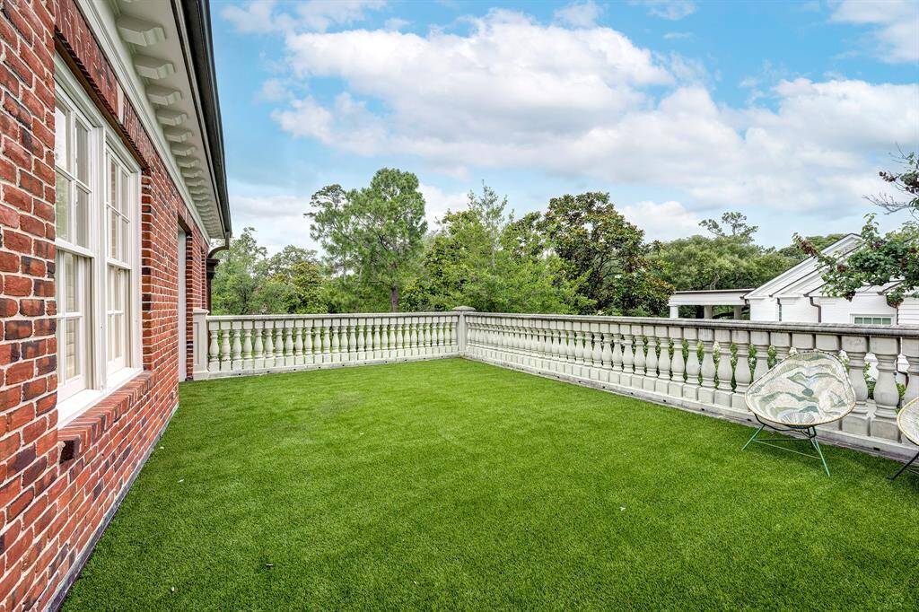 The second-floor landing features a terrace with turf and a cast stone railing, offering the perfect spot for al fresco dining.