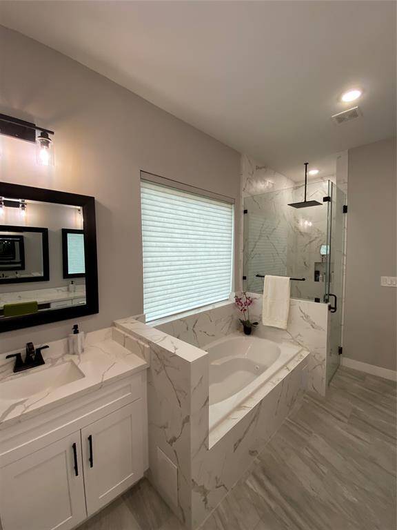 Primary bathroom features jetted tub, his and hers separate vanities, large curbless shower featuring rain shower and hand held sprayer