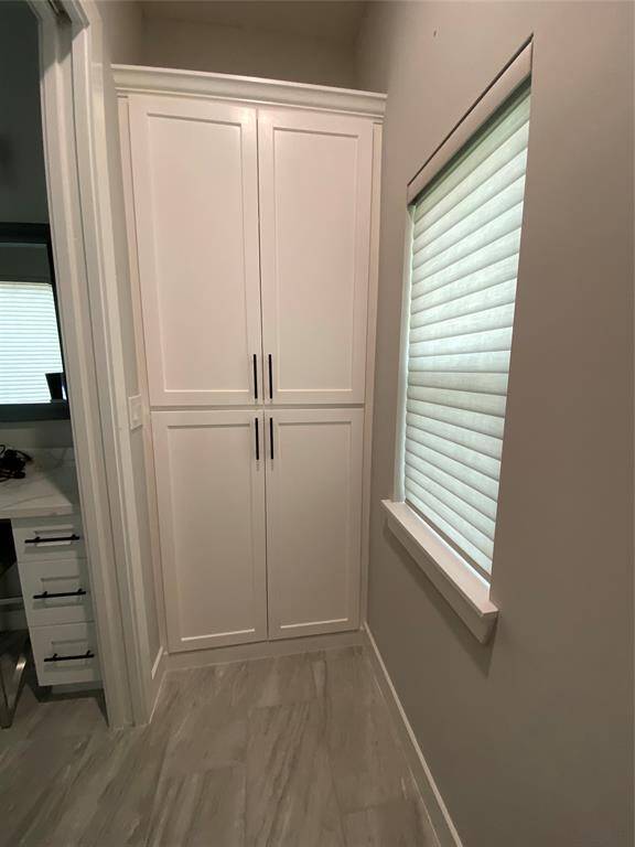 A pocket door separates primary water closet area and features a custom built cabinet for added storage of linens and supplies.