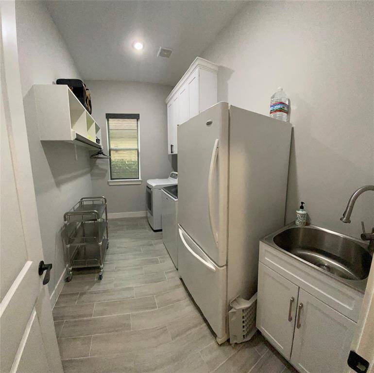 Large utility room has plenty of storage with custom cabinets and shelves with hanging rods. Washer/dryer and frig can remain.