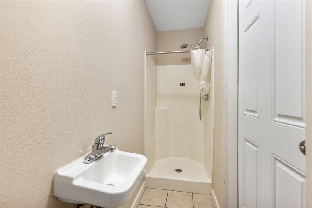 This bathroom is the third bathroom of the property and features a shower and sink—perfect for rinsing off pool water or a day in the sun. Door for entry is located on right side of garage to left of pool.