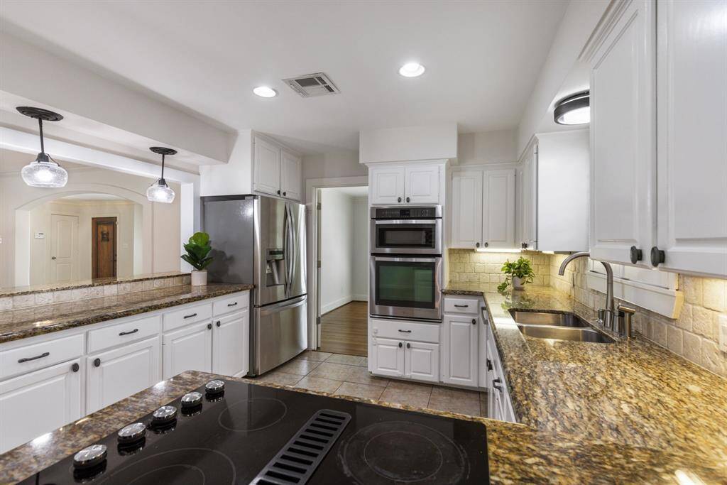 The kitchen offers a warm and inviting atmosphere, with the perfect balance of natural light and built-in lighting, including under-cabinet illumination. It seamlessly opens to the spacious living area.