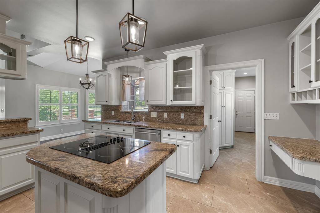 The large center island features a built-in electric cooktop and is illuminated by two updated pendant lights, adding both function and style to this inviting kitchen space.