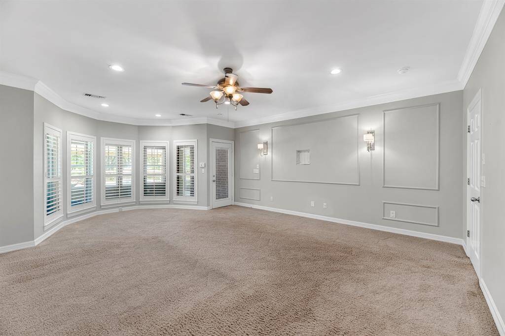 The spacious primary suite offers plush carpeting, elegant crown molding, and soft decorator tones. A beautiful bay of windows creates the perfect nook for a cozy seating area, filling the room with natural light.