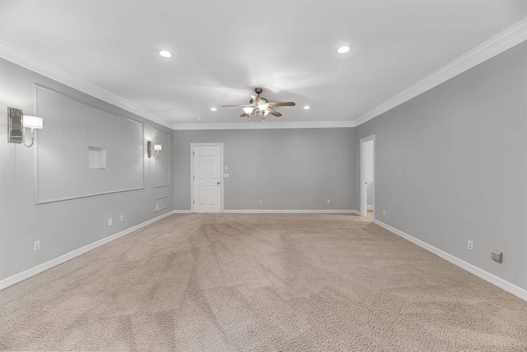This expansive primary bedroom easily accommodates a king-size bed and includes ample wall space for a media setup. An elegant accent wall with custom sconces adds a touch of sophistication to this peaceful retreat.