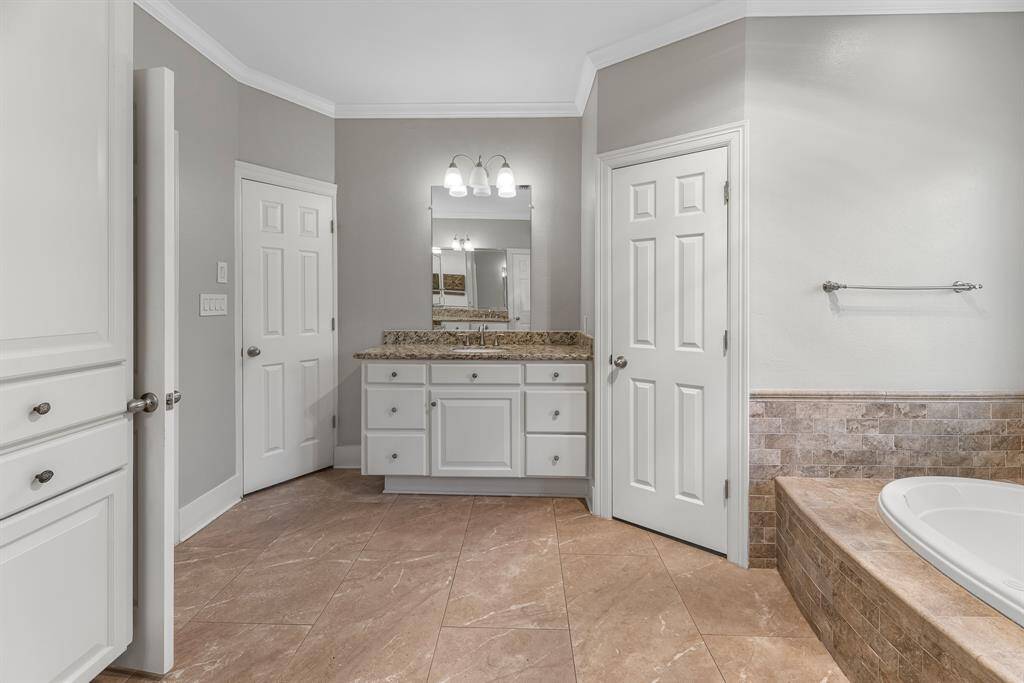 This view highlights the second vanity, featuring granite countertops, crisp white cabinetry, brushed nickel finishes, and an updated light fixture. With abundant storage, the space is as functional as it is stylish.
