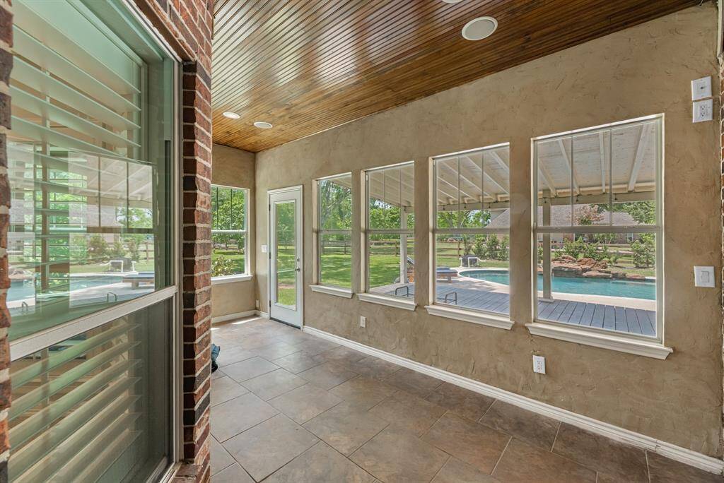 Just off the primary bedroom, the bright sunroom boasts tile floors, a tongue and groove ceiling, and walls of windows overlooking the pool—an ideal spot for morning coffee or relaxing with a good book.
